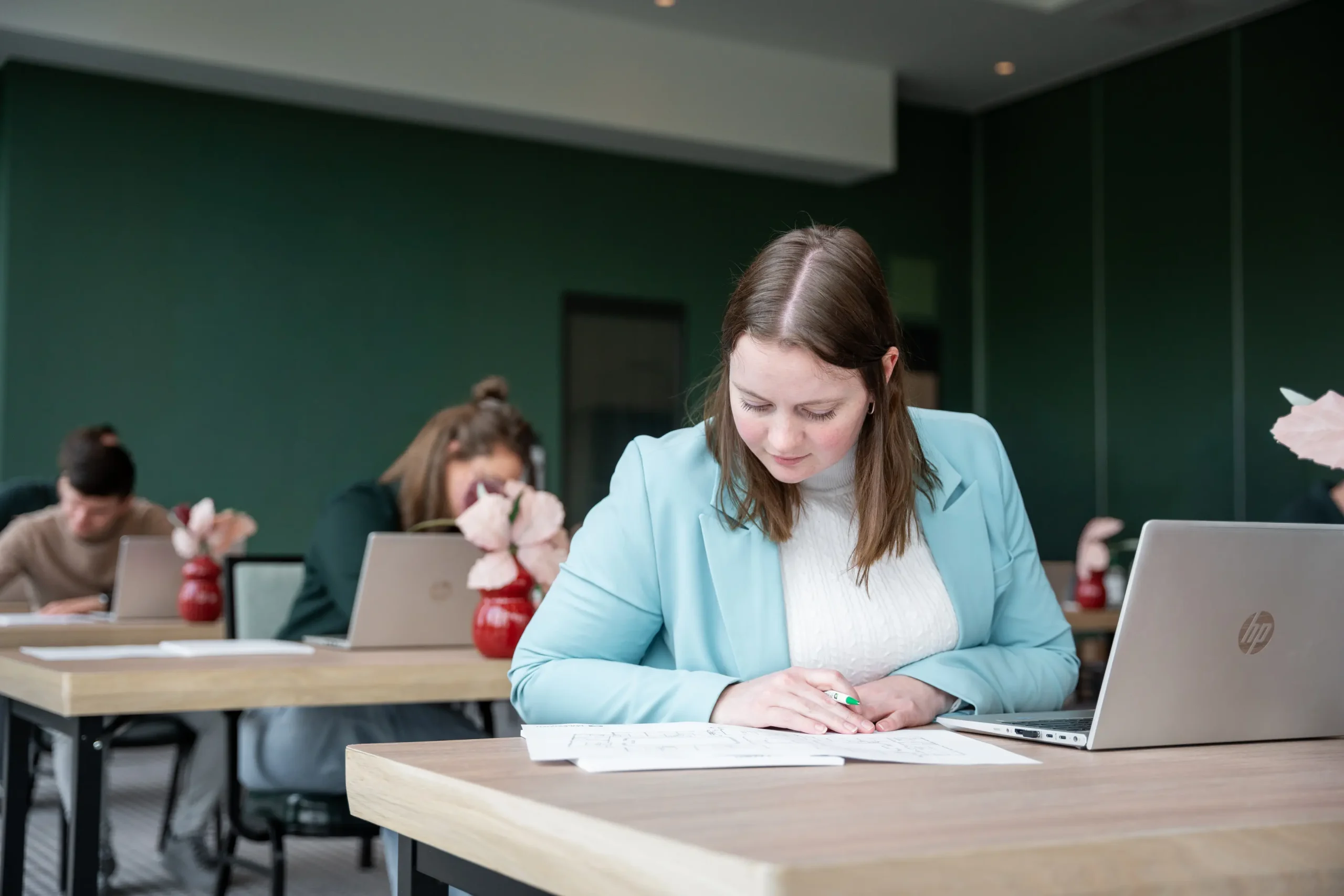 Vrouw die papieren leest en een laptop voor zich heeft