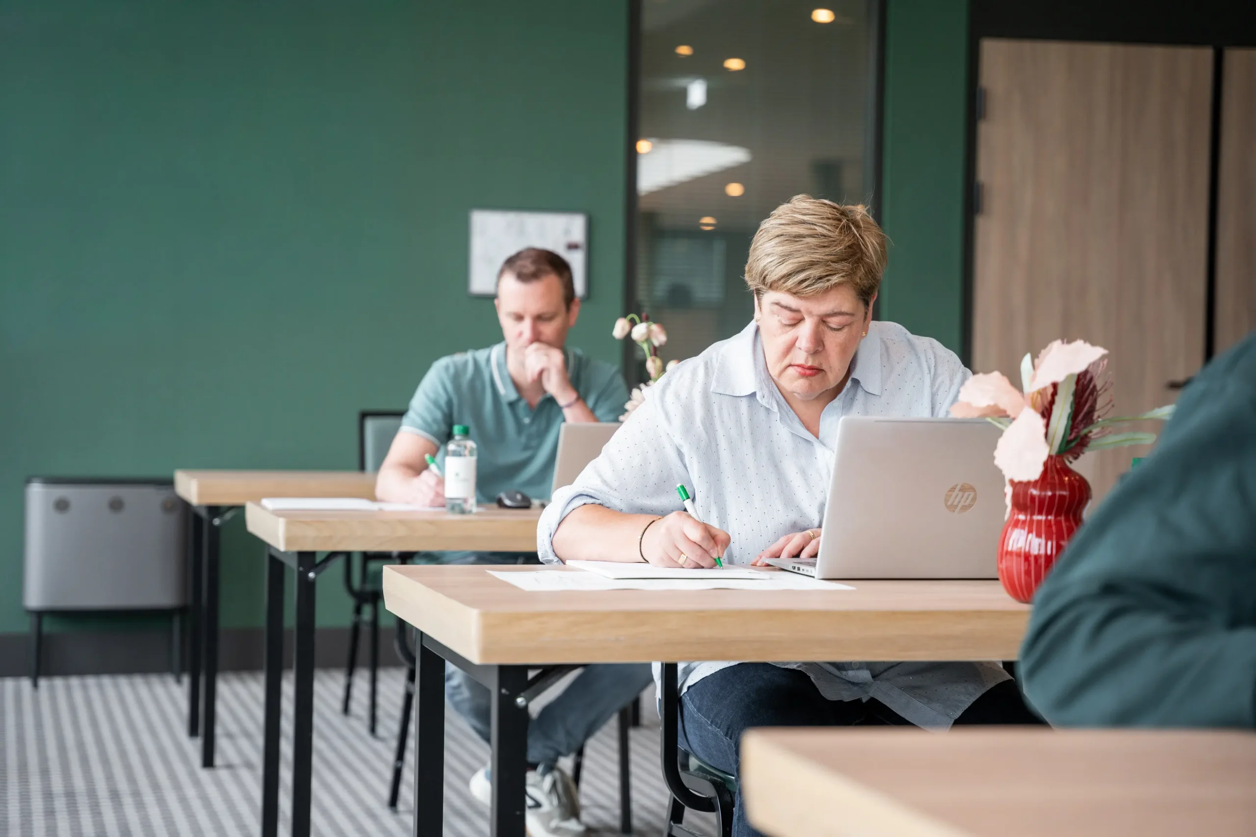 Vrouw die schrijft en een laptop tijdens een examen
